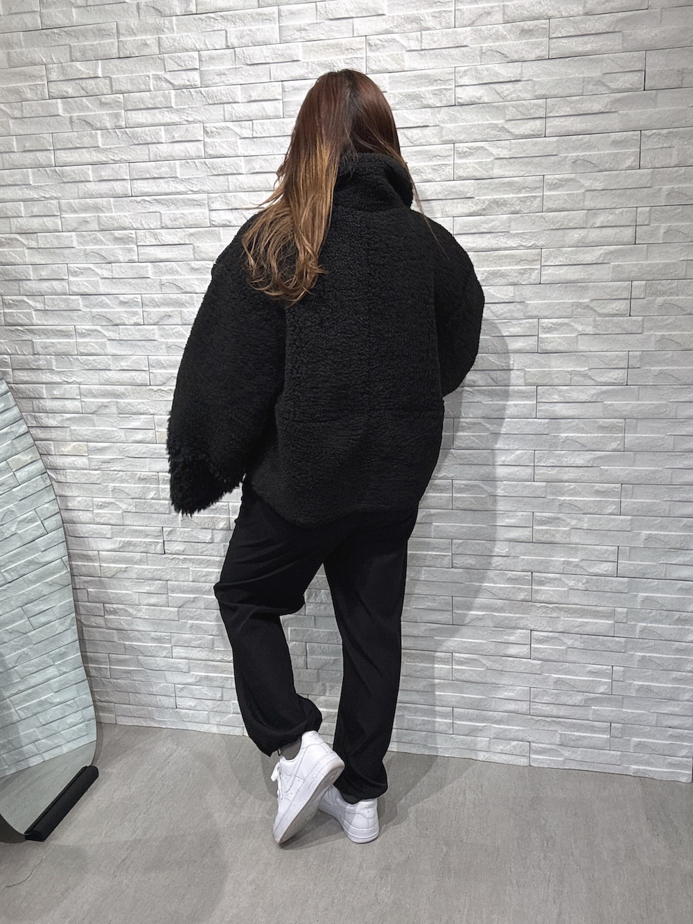 ブラック系のムートンコート、グレー系のニット/セーター、ブラック系のその他パンツを着用したレディースの冬コーディネートの3枚目の写真