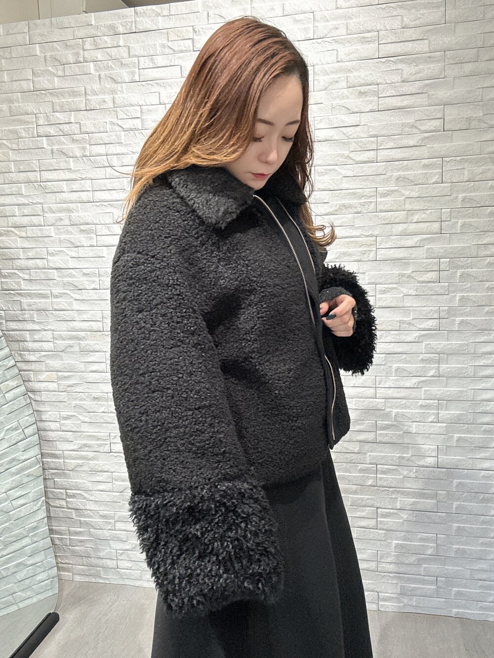 ブラック系のムートンコート、グレー系のニット/セーター、ブラック系のスカートを着用したレディースの冬コーディネートの4枚目の写真