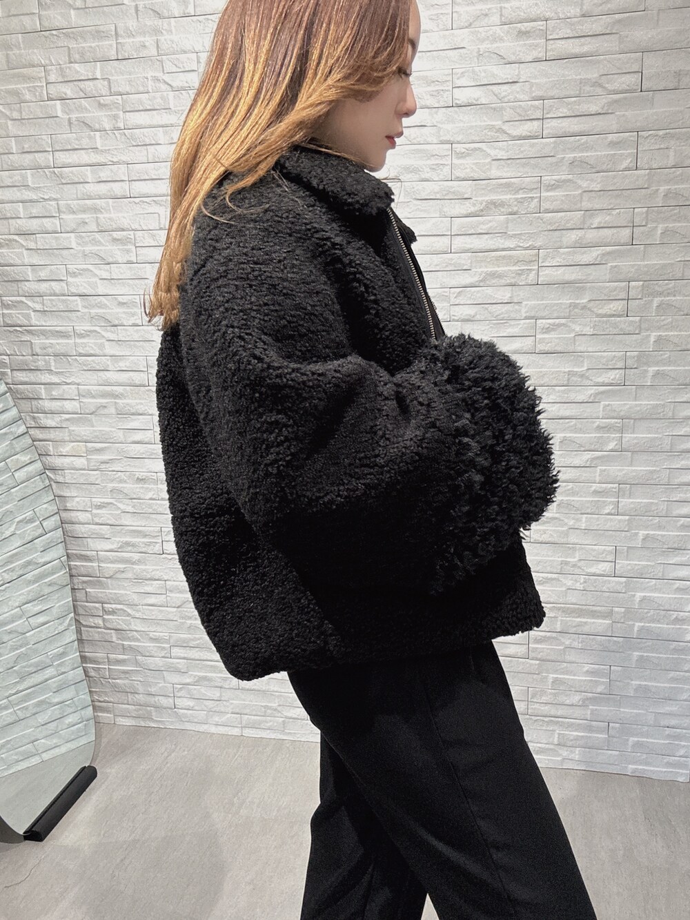 ブラック系のムートンコート、グレー系のニット/セーター、ブラック系のその他パンツを着用したレディースの冬コーディネートの5枚目の写真