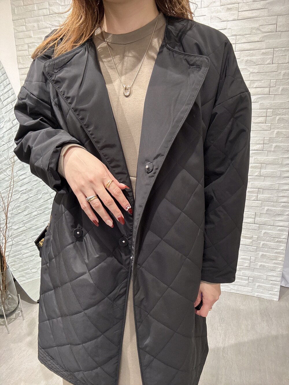 ブラック系のノーカラーコート、グリーン系のワンピースを着用したレディースの冬コーディネートの3枚目の写真