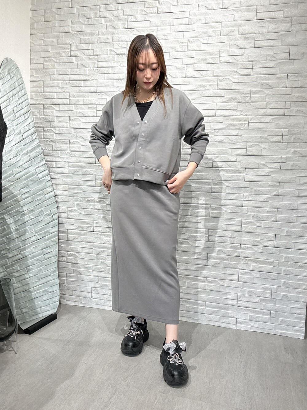 グレー系のスカート、グレー系のカーディガン/ボレロ、ブラック系のタンクトップを着用したレディースの春コーディネートの2枚目の写真