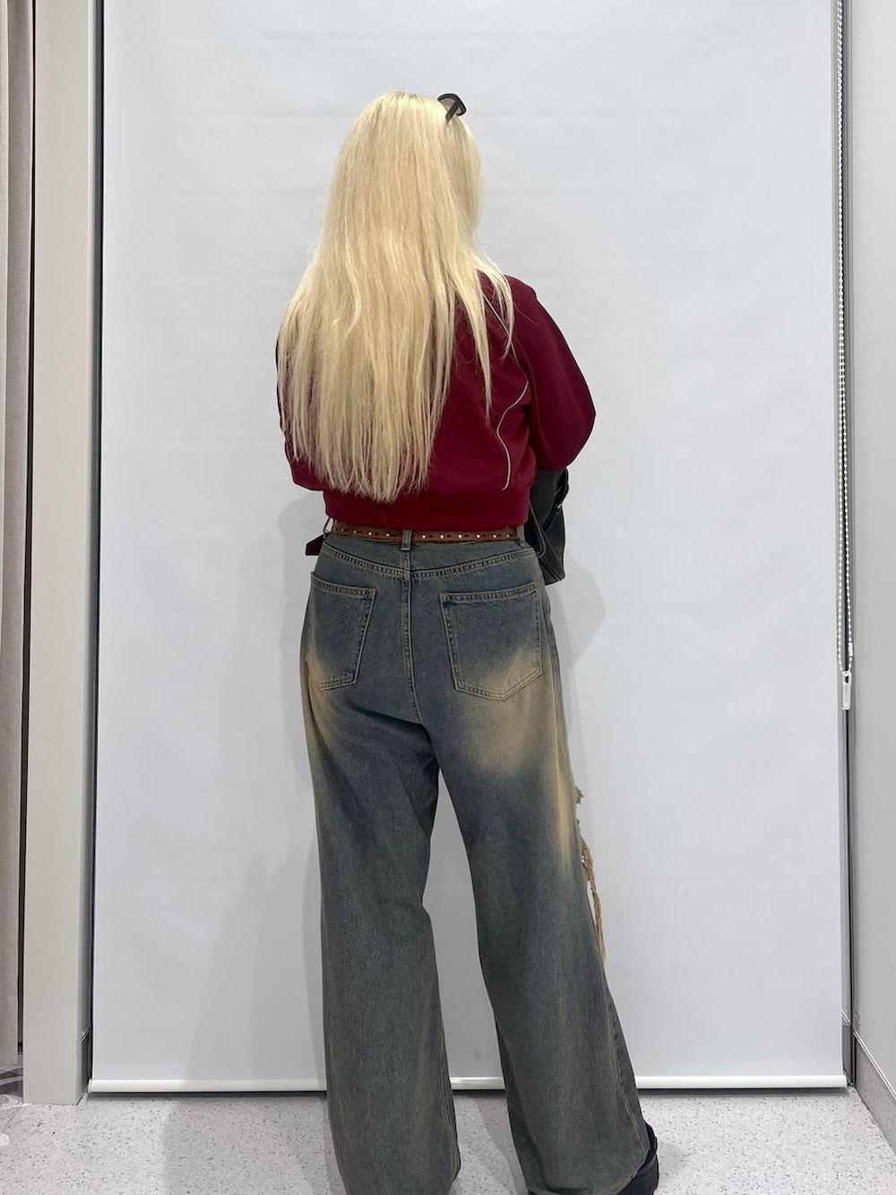 ブルー系のデニムパンツ、ブラック系のショルダーバッグ、レッド系のブルゾンを着用したレディースの夏コーディネートの4枚目の写真