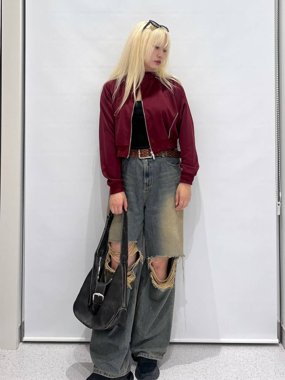 ブルー系のデニムパンツ、ブラック系のショルダーバッグ、レッド系のブルゾンを着用したレディースの夏コーディネートの2枚目の写真