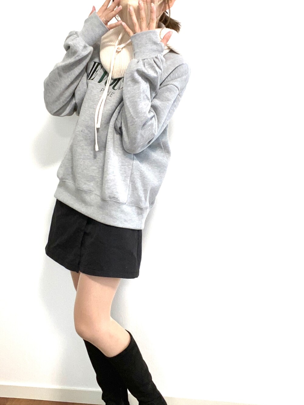 グレー系のスウェット、ブラック系のブーツ、ホワイト系のマフラーを着用したレディースの秋コーディネートの2枚目の写真