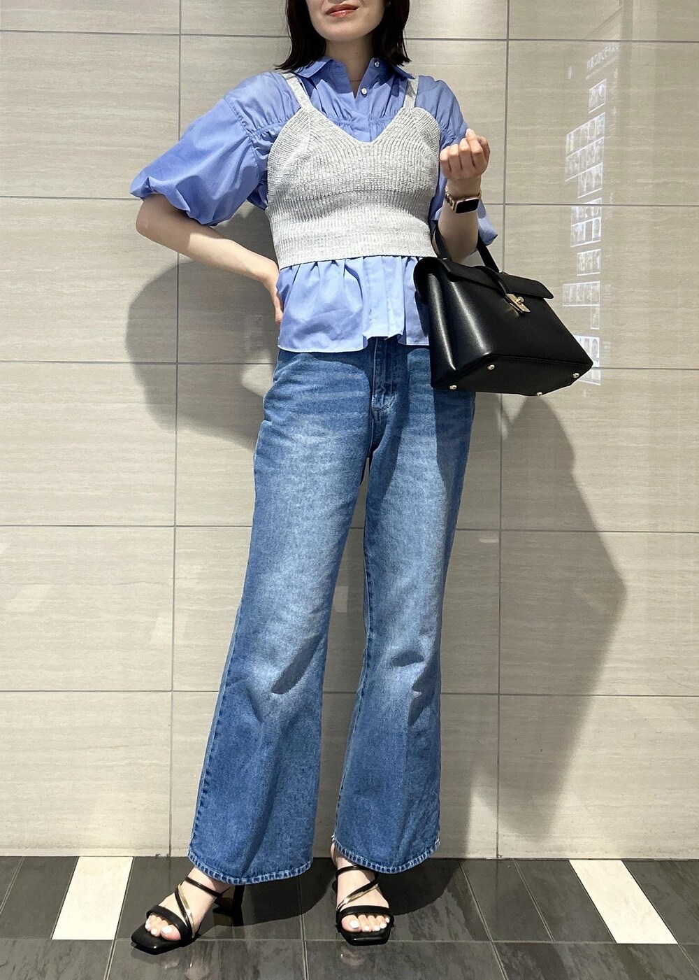 ブラック系のハンドバッグ、ブルー系のデニムパンツ、ブラック系のサンダルを着用したレディースの春コーディネートの4枚目の写真