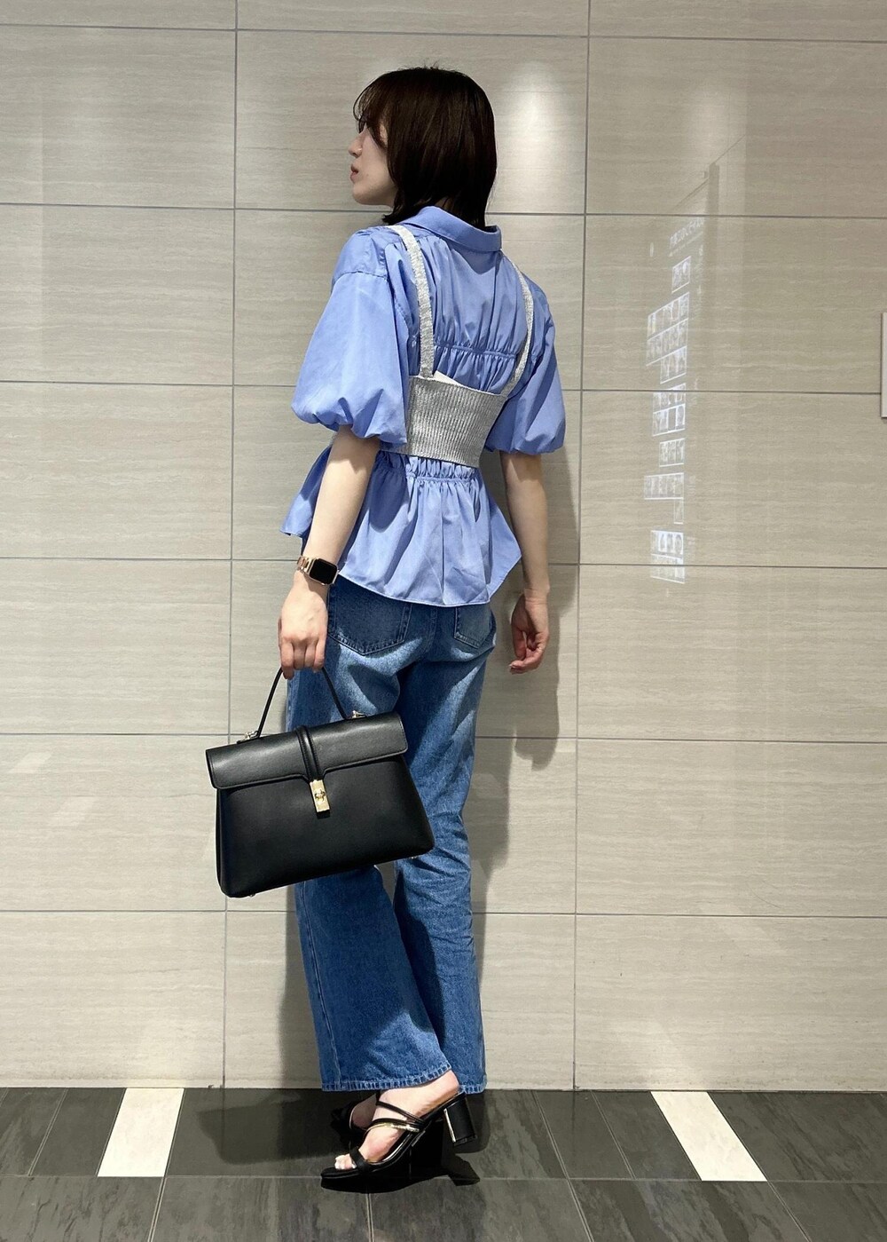 ブラック系のハンドバッグ、ブルー系のデニムパンツ、ブラック系のサンダルを着用したレディースの春コーディネートの3枚目の写真
