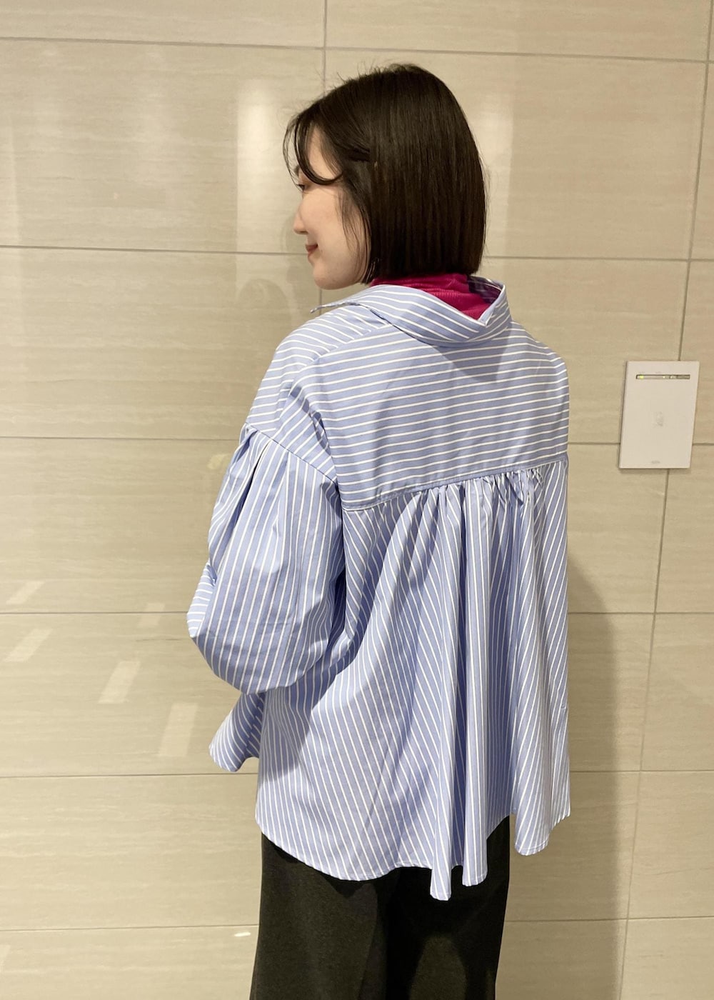 ピンク系のTシャツ/カットソー、ゴールド系のハンドバッグ、グレー系のスラックスを着用したレディースの冬コーディネートの5枚目の写真