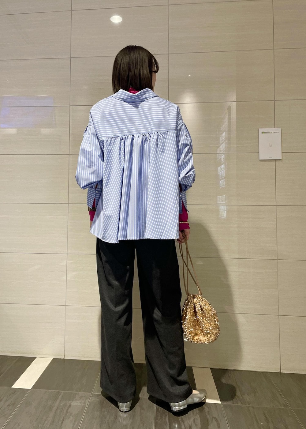 ピンク系のTシャツ/カットソー、ゴールド系のハンドバッグ、グレー系のスラックスを着用したレディースの冬コーディネートの3枚目の写真