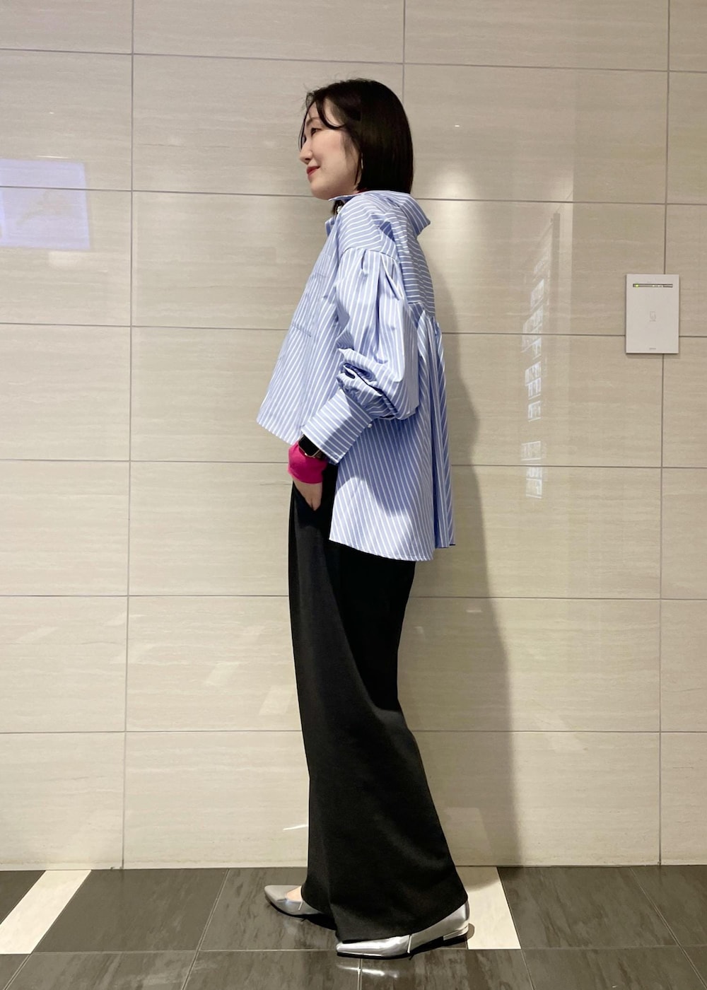 ピンク系のTシャツ/カットソー、ゴールド系のハンドバッグ、グレー系のスラックスを着用したレディースの冬コーディネートの2枚目の写真