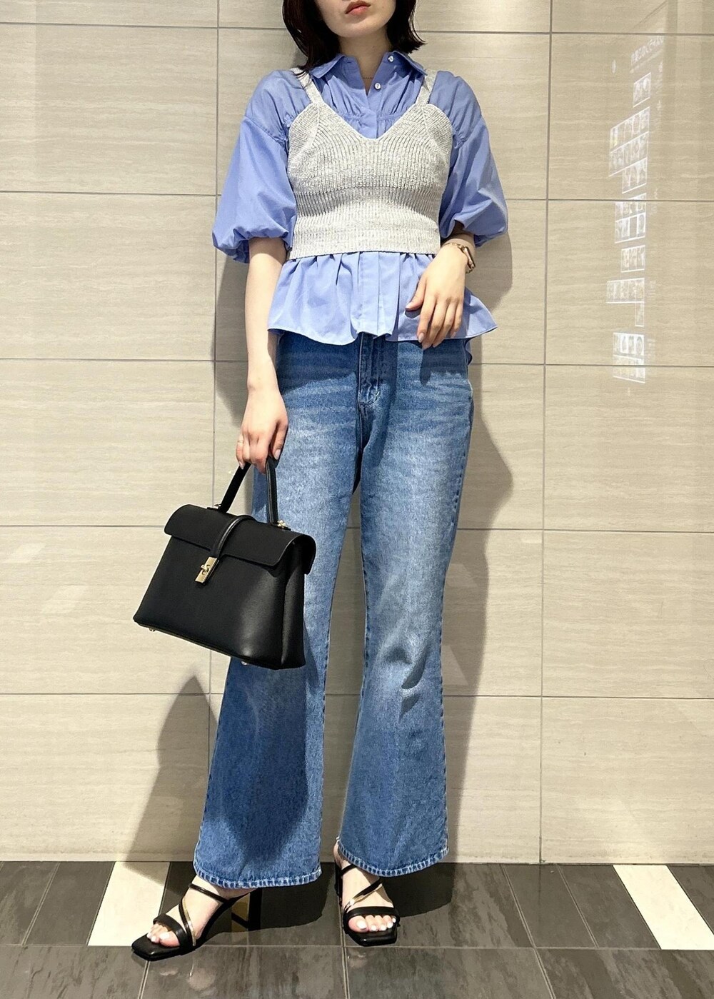 ブラック系のハンドバッグ、ブルー系のデニムパンツ、ブラック系のサンダルを着用したレディースの春コーディネートの5枚目の写真