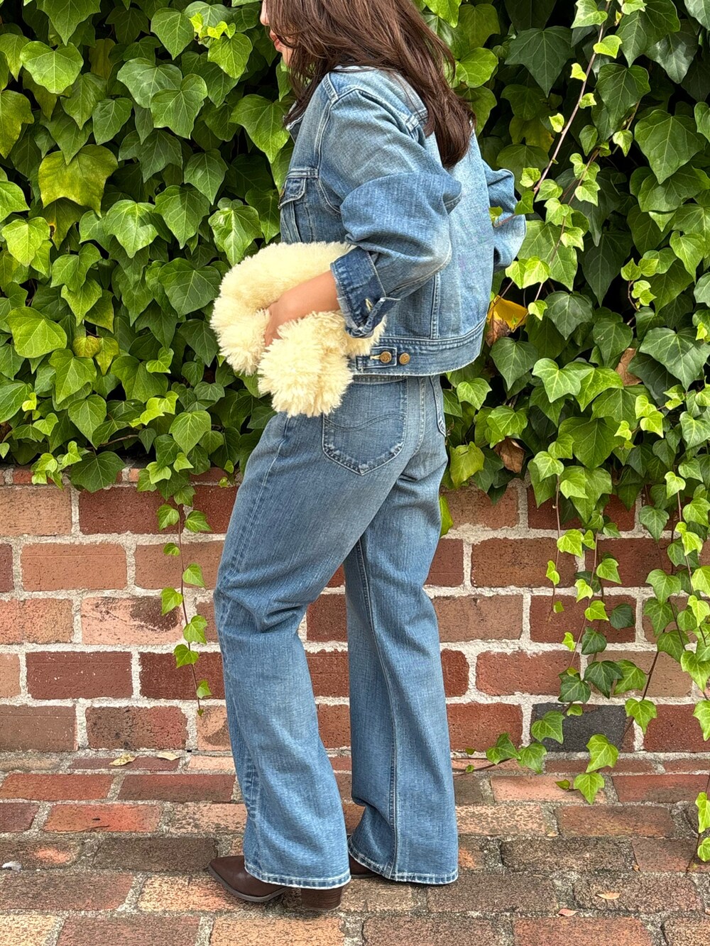 ブルー系のデニムジャケット、ブルー系のデニムパンツ、ブラウン系のブーツを着用したレディースの秋コーディネートの2枚目の写真