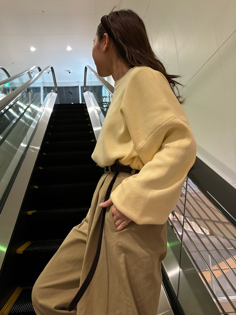 ベージュ系のチノパンツ、ブラウン系のブーツ、イエロー系のニット/セーターを着用したレディースの冬コーディネートの5枚目の写真