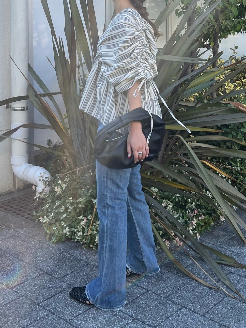 ブルー系のデニムパンツ、ホワイト系のハンドバッグ、ホワイト系のシャツ/ブラウスを着用したレディースの夏コーディネートの2枚目の写真