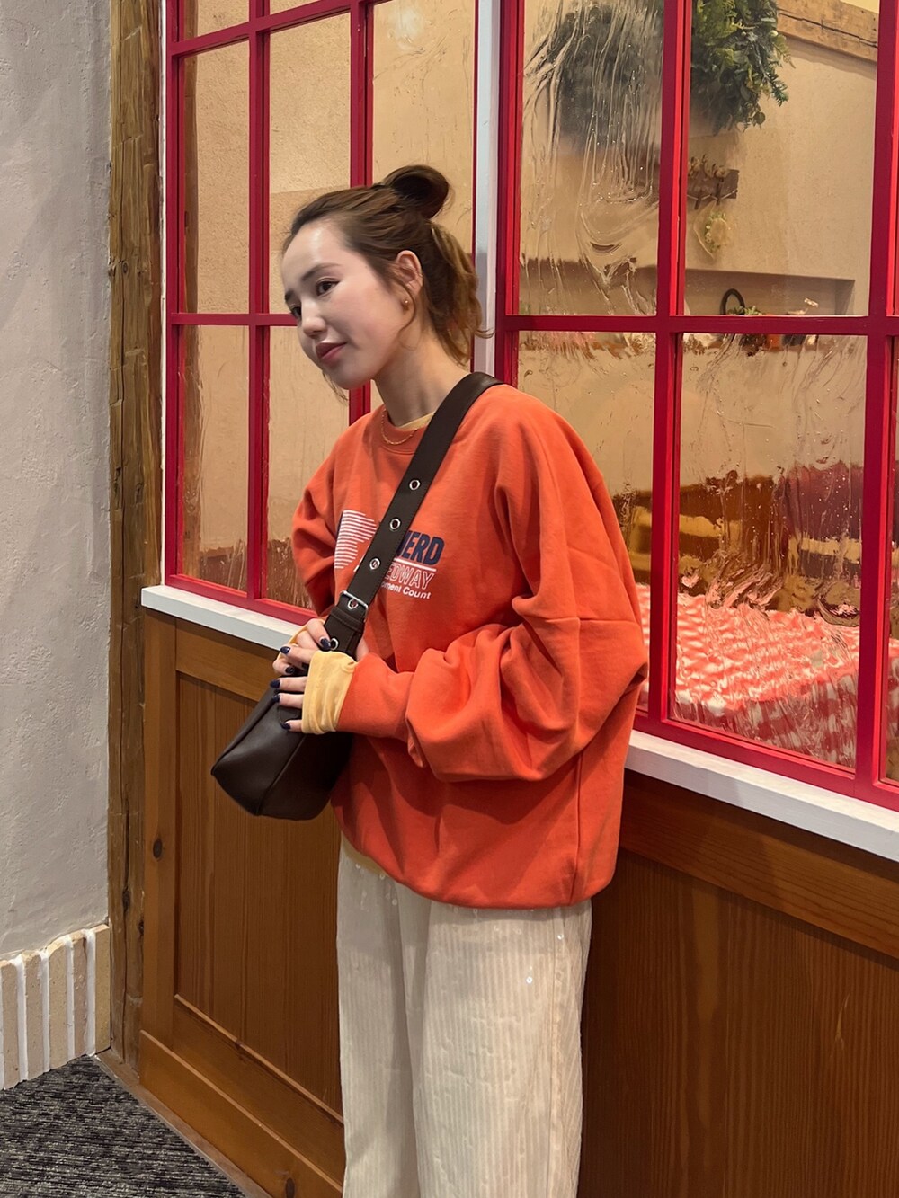 オレンジ系のTシャツ/カットソー、オレンジ系のスウェット、ホワイト系のその他パンツを着用したレディースの冬コーディネートの2枚目の写真