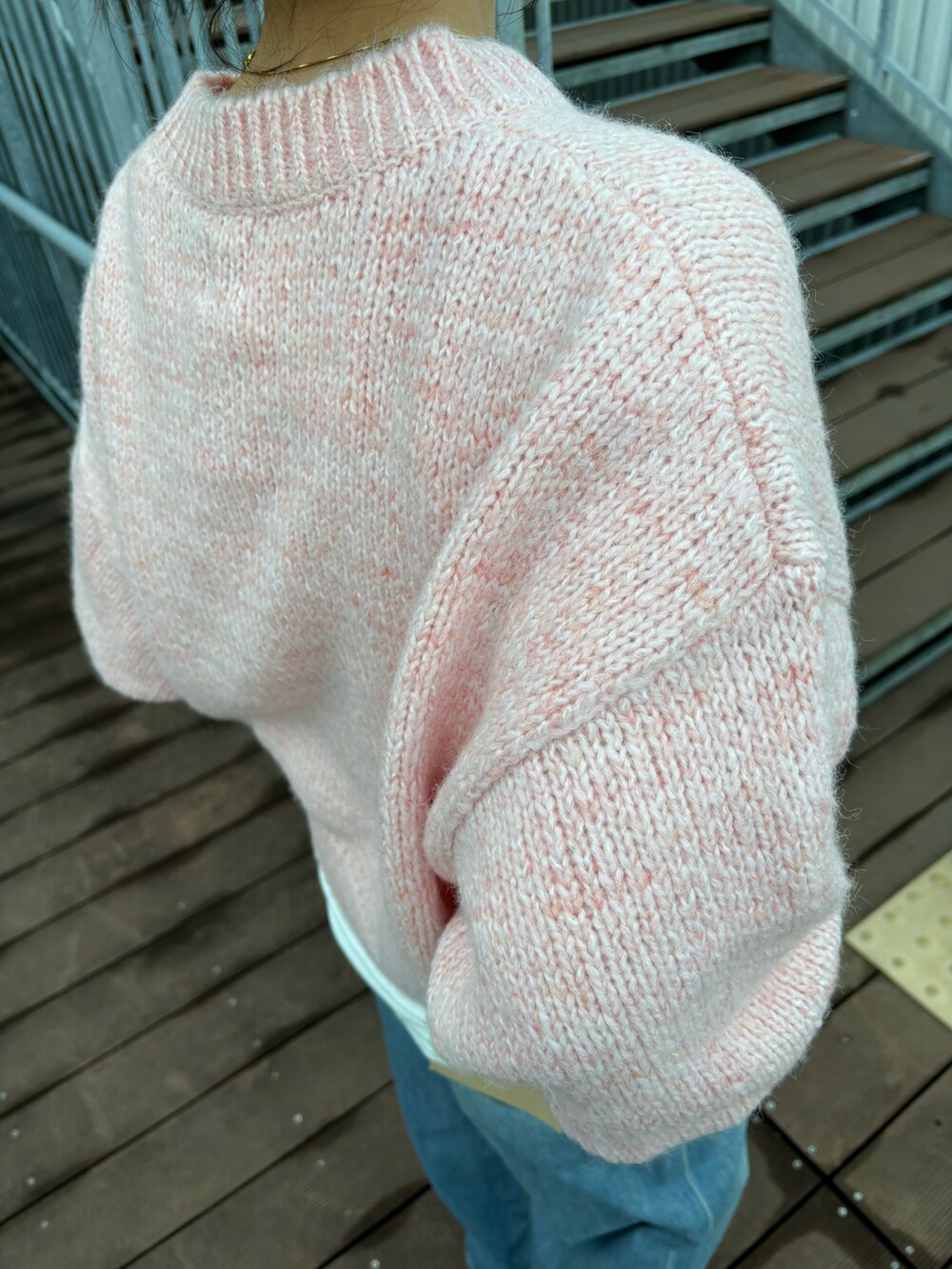 ピンク系のニット/セーター、ブルー系のデニムパンツを着用したレディースの秋コーディネートの4枚目の写真