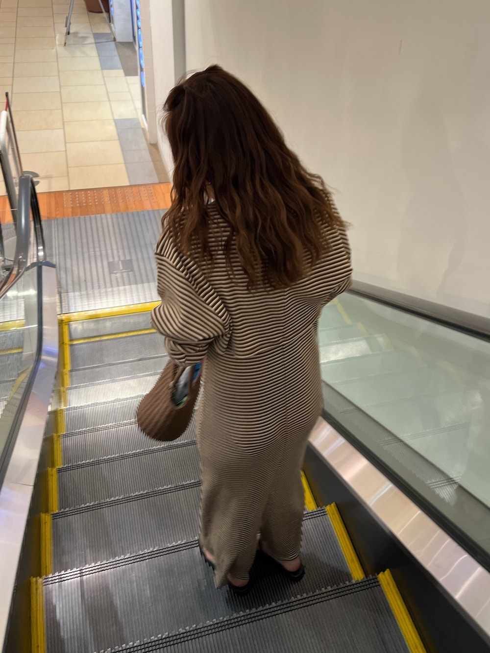 ブラウン系のワンピース、ブラウン系のかごバッグ、ホワイト系のサンダルを着用したレディースの夏コーディネートの2枚目の写真