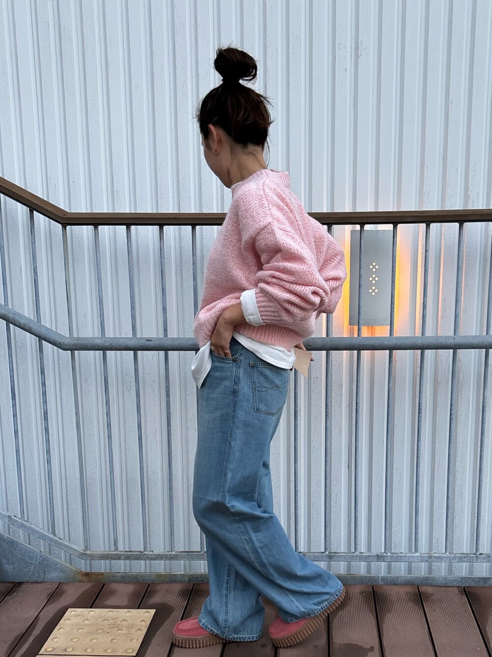 ピンク系のニット/セーター、ブルー系のデニムパンツを着用したレディースの秋コーディネートの2枚目の写真