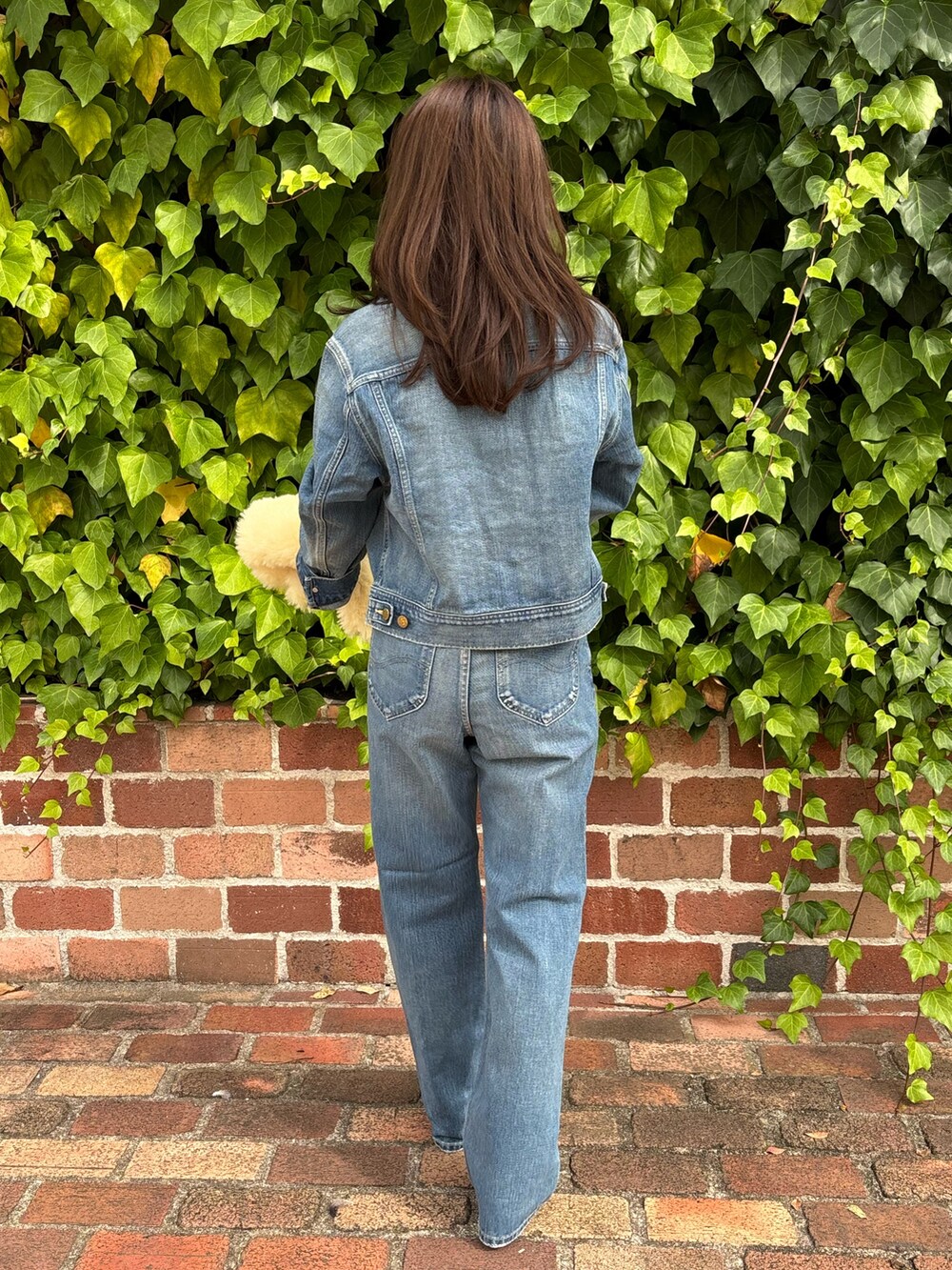 ブルー系のデニムジャケット、ブルー系のデニムパンツ、ブラウン系のブーツを着用したレディースの秋コーディネートの3枚目の写真