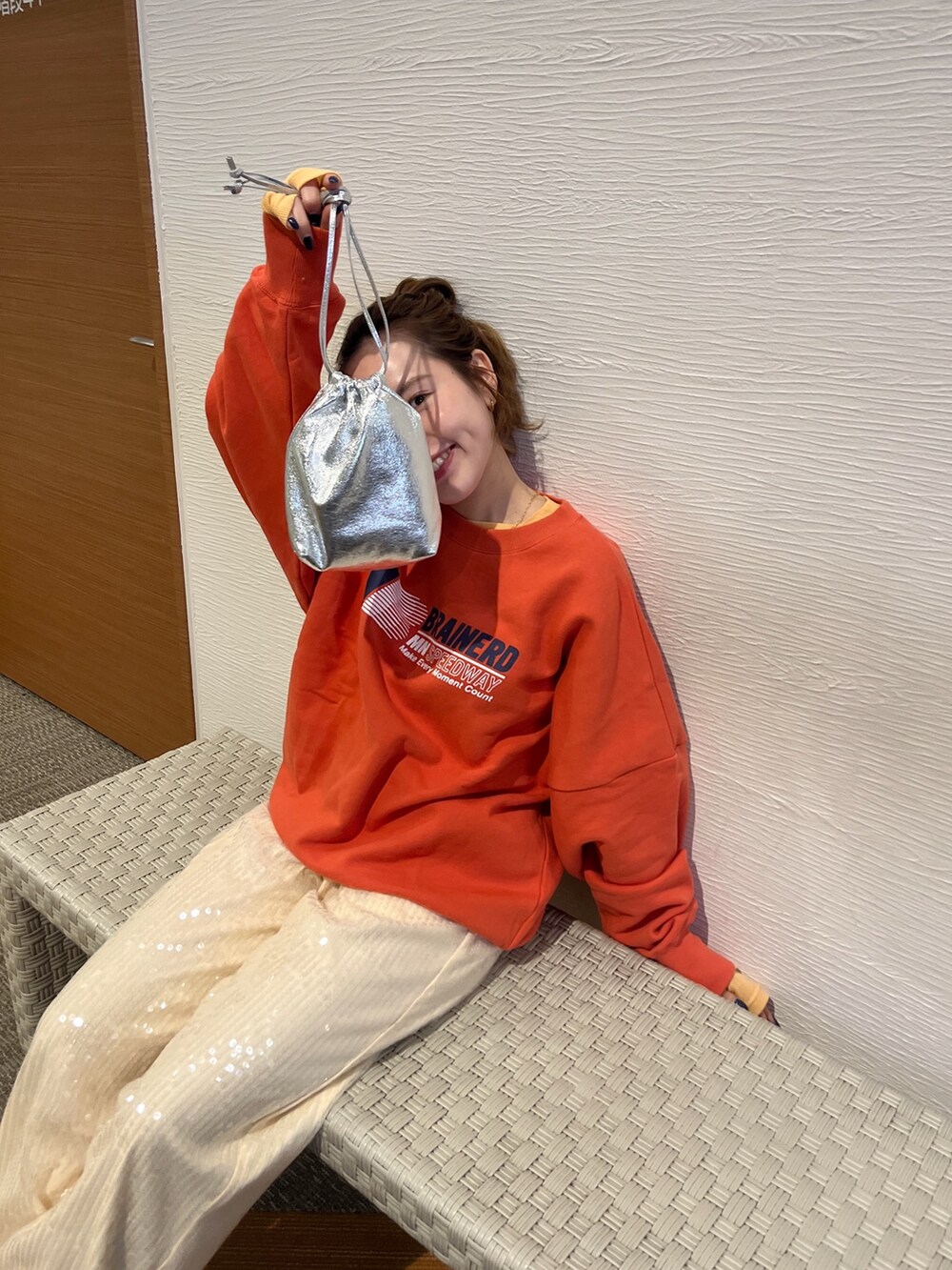 オレンジ系のTシャツ/カットソー、オレンジ系のスウェット、ホワイト系のその他パンツを着用したレディースの冬コーディネートの3枚目の写真