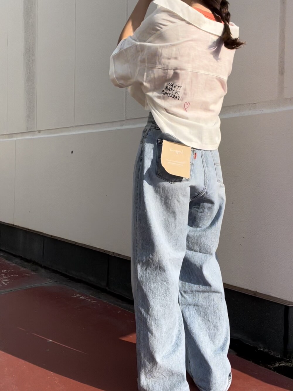 ブルー系のデニムパンツ、オレンジ系のタンクトップ、ブラック系のサンダルを着用したレディースの夏コーディネートの2枚目の写真