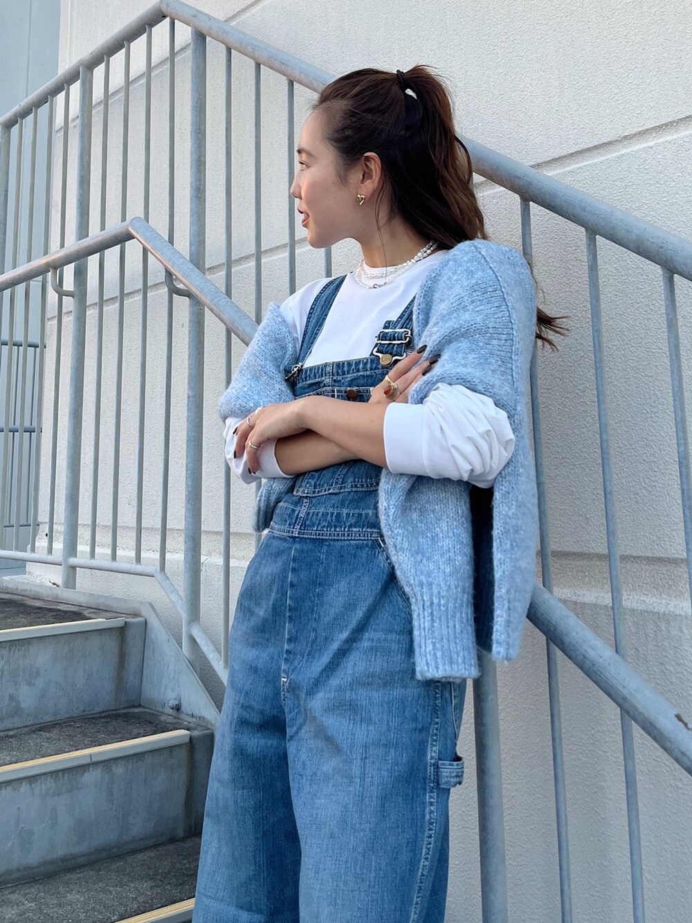 ブルー系のサロペット/オーバーオール、ブルー系のニット/セーター、ホワイト系のTシャツ/カットソーを着用したレディースの秋コーディネートの3枚目の写真