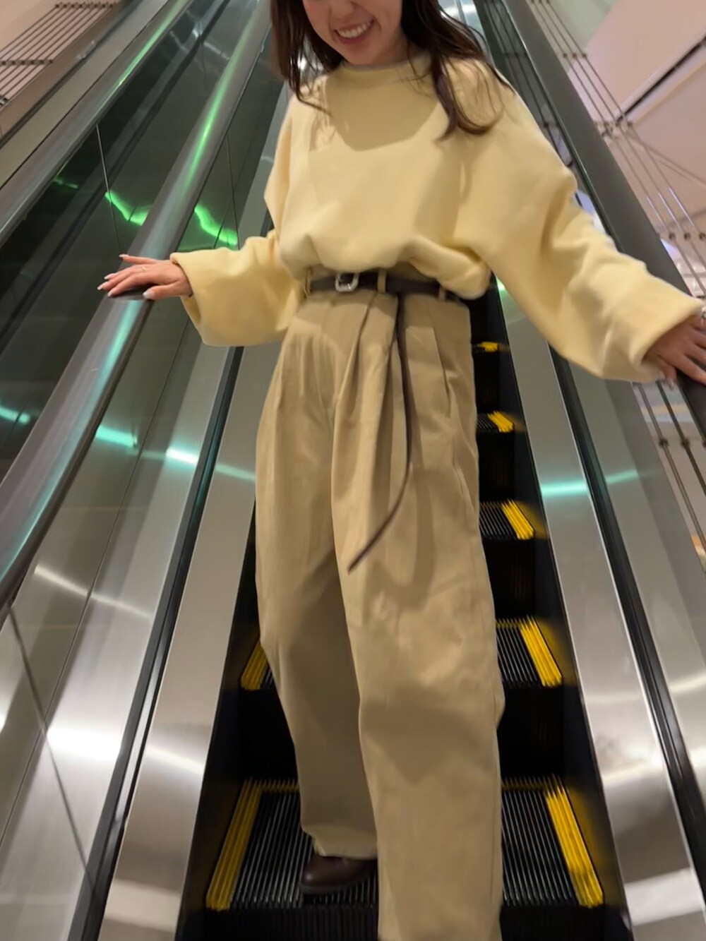 ベージュ系のチノパンツ、ブラウン系のブーツ、イエロー系のニット/セーターを着用したレディースの冬コーディネートの4枚目の写真