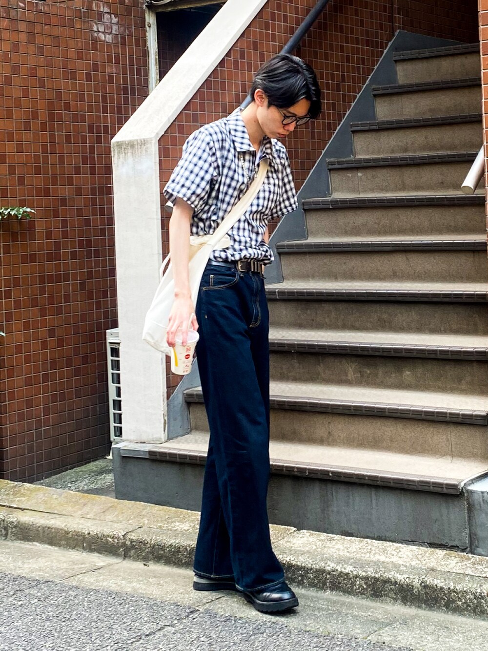 ブルー系のデニムパンツ、ブラック系のドレスシューズ、ブラック系のトップスを着用したメンズの夏コーディネートの3枚目の写真