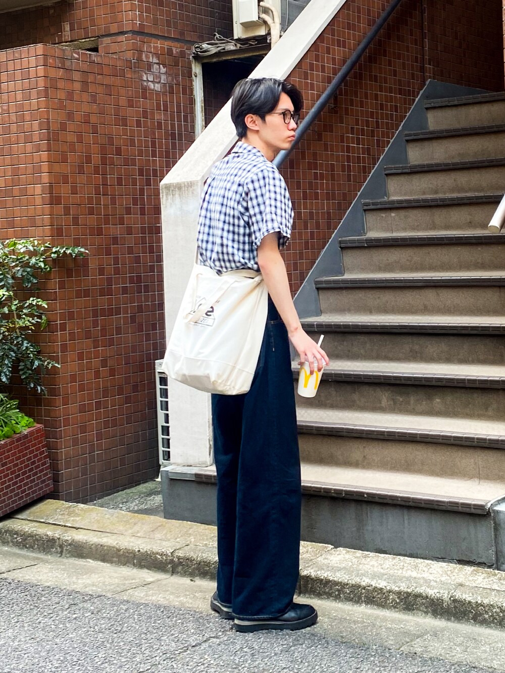 ブルー系のデニムパンツ、ブラック系のドレスシューズ、ブラック系のトップスを着用したメンズの夏コーディネートの2枚目の写真