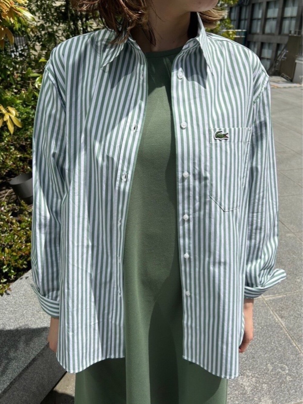 グリーン系のシャツ/ブラウス、グリーン系のワンピース、グレー系のスニーカーを着用したレディースの春コーディネートの5枚目の写真