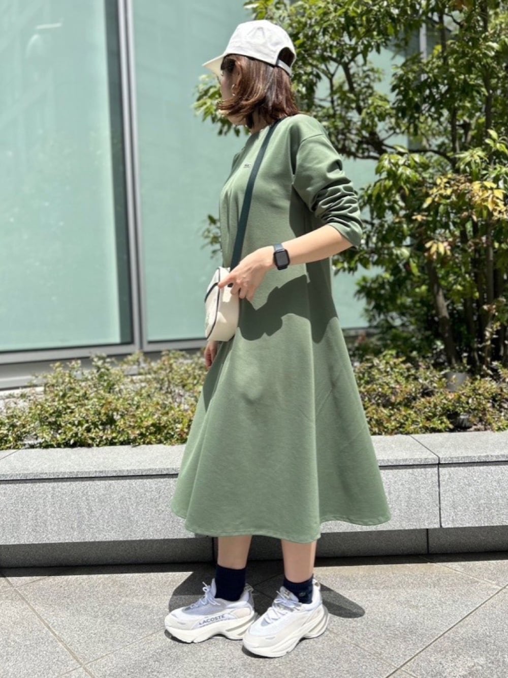 グリーン系のシャツ/ブラウス、グリーン系のワンピース、グレー系のスニーカーを着用したレディースの春コーディネートの3枚目の写真