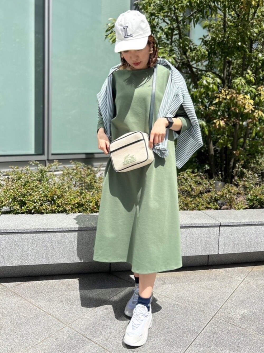 グリーン系のシャツ/ブラウス、グリーン系のワンピース、グレー系のスニーカーを着用したレディースの春コーディネートの2枚目の写真