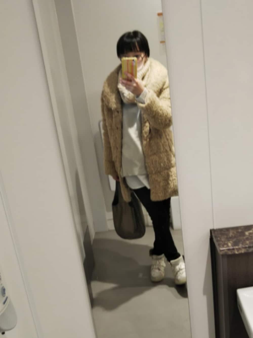 ベージュ系のダウンジャケット/コート、グレー系のニット/セーター、ブラック系のデニムパンツを着用したレディースの冬コーディネートの2枚目の写真
