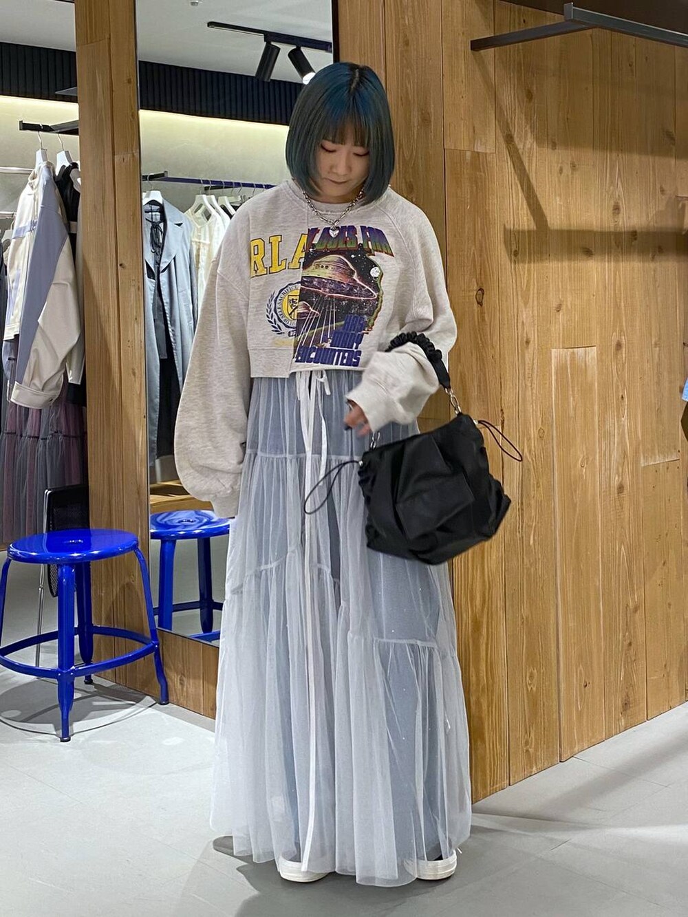 ベージュ系のスウェット、ブルー系のデニムパンツ、ホワイト系のワンピースを着用したレディースの春コーディネートの4枚目の写真