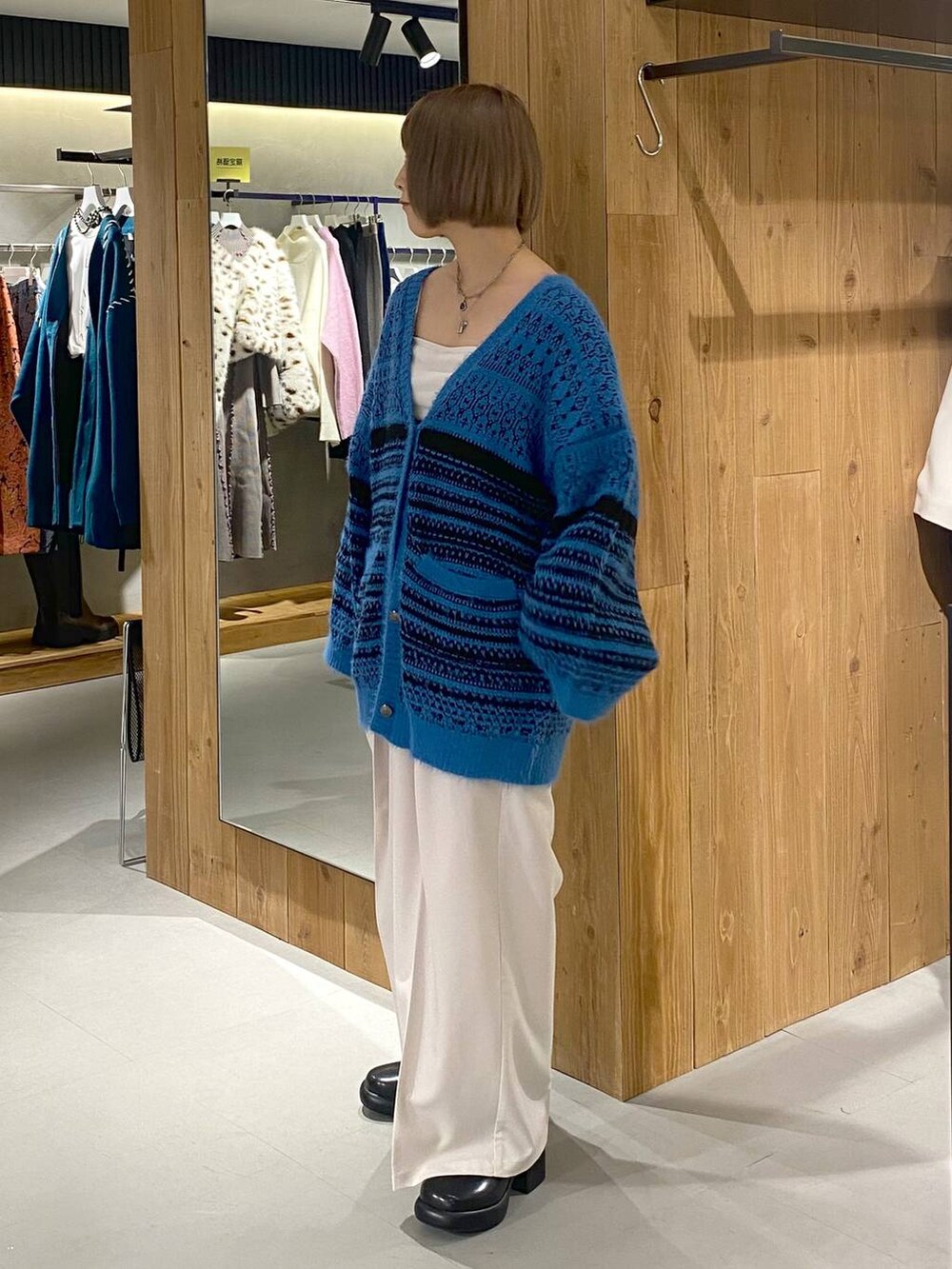 ホワイト系のキャミソール、ブラック系のブーツ、ベージュ系のスラックスを着用したレディースの冬コーディネートの2枚目の写真