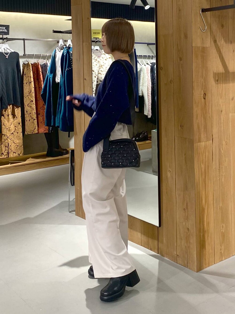 ホワイト系のキャミソール、ブラック系のブーツ、ベージュ系のスラックスを着用したレディースの冬コーディネートの3枚目の写真