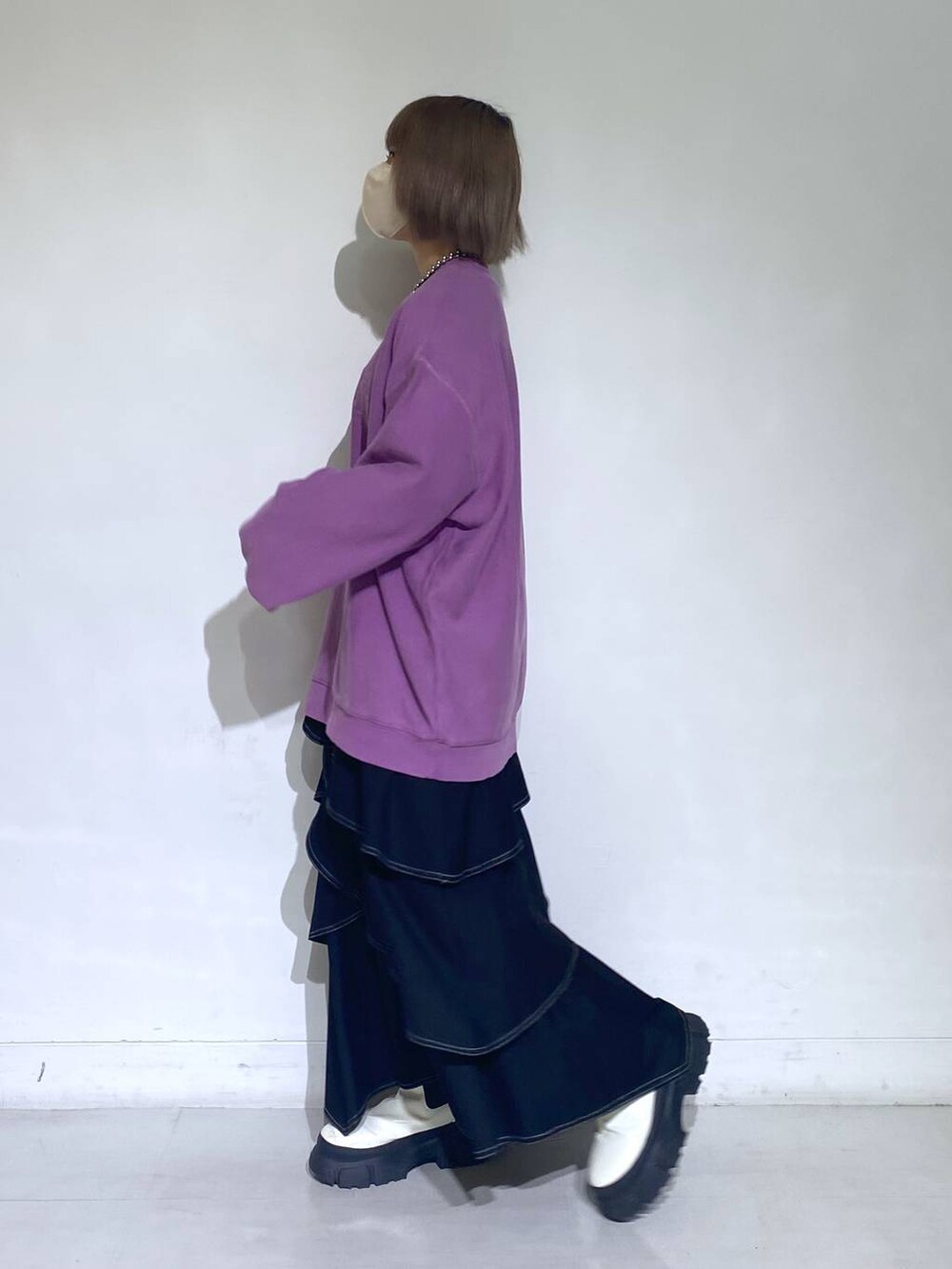 パープル系のスウェット、ホワイト系のブーツ、ブラック系のスカートを着用したレディースの冬コーディネートの2枚目の写真