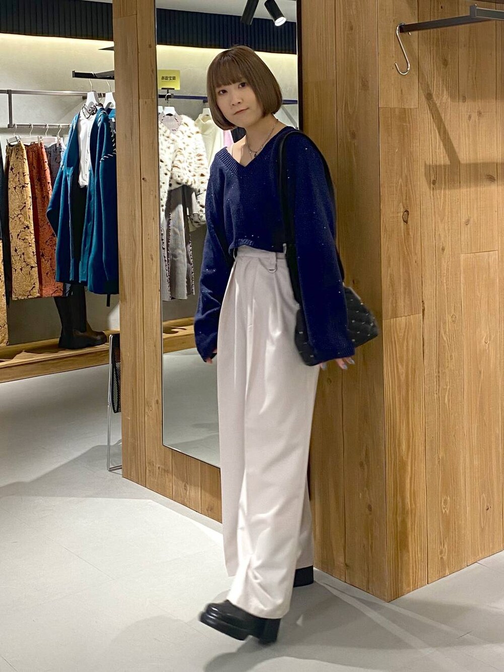 ホワイト系のキャミソール、ブラック系のブーツ、ベージュ系のスラックスを着用したレディースの冬コーディネートの2枚目の写真