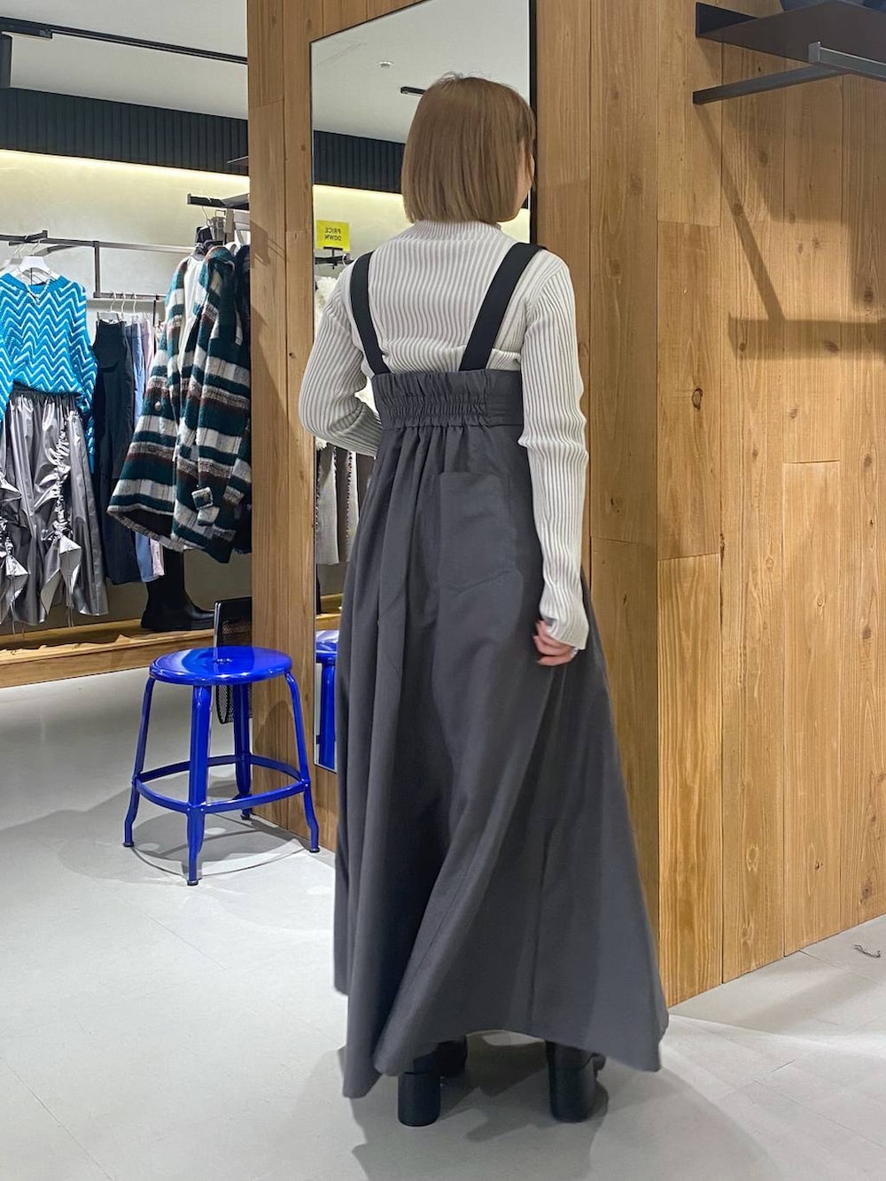 グレー系のジャンパースカート、ブラック系のブーツ、ホワイト系のニット/セーターを着用したレディースの冬コーディネートの5枚目の写真