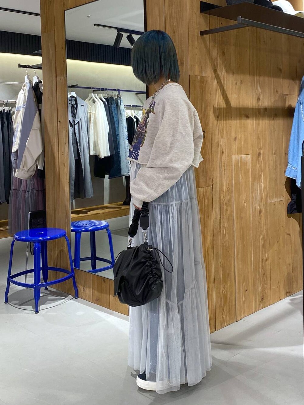 ベージュ系のスウェット、ブルー系のデニムパンツ、ホワイト系のワンピースを着用したレディースの春コーディネートの2枚目の写真