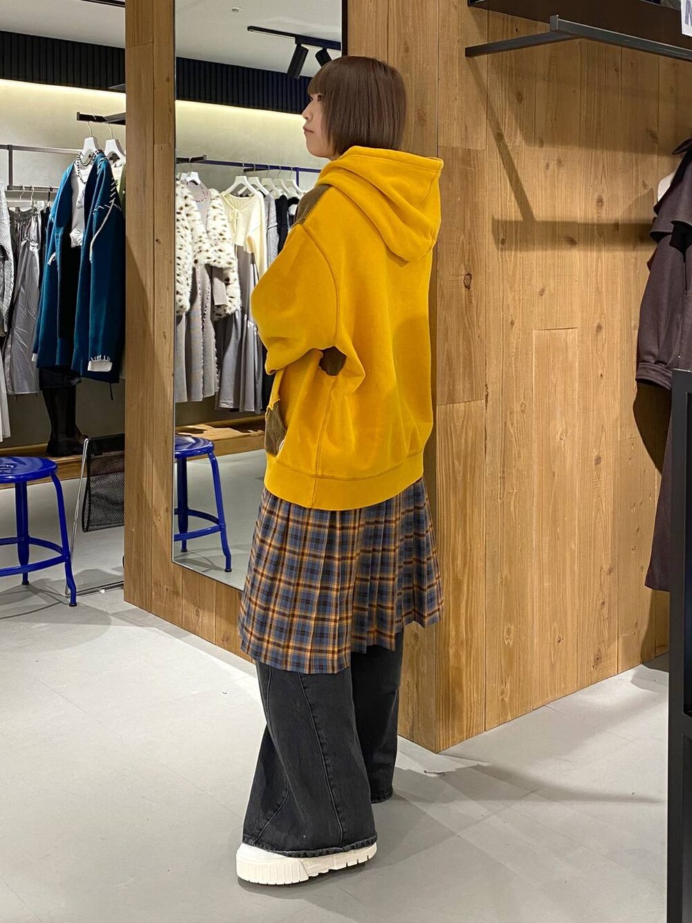 ブラック系のデニムパンツ、イエロー系のパーカー、オレンジ系のスカートを着用したレディースの秋コーディネートの2枚目の写真