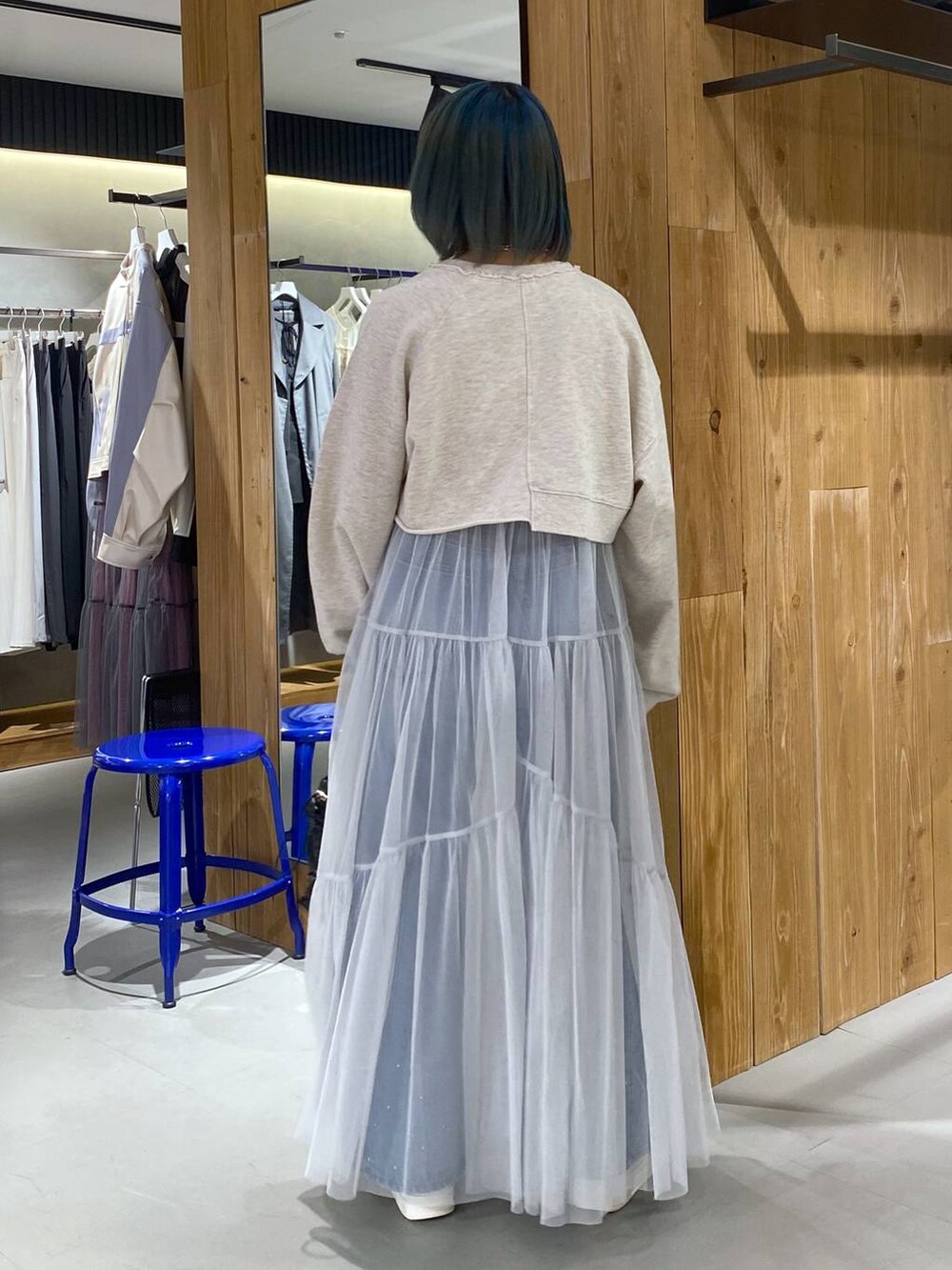 ベージュ系のスウェット、ブルー系のデニムパンツ、ホワイト系のワンピースを着用したレディースの春コーディネートの5枚目の写真