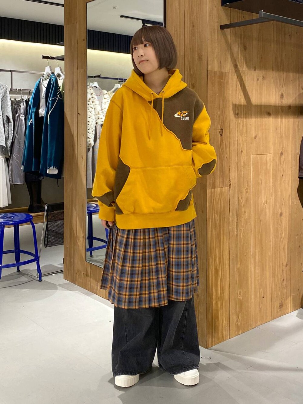 ブラック系のデニムパンツ、イエロー系のパーカー、オレンジ系のスカートを着用したレディースの秋コーディネートの3枚目の写真