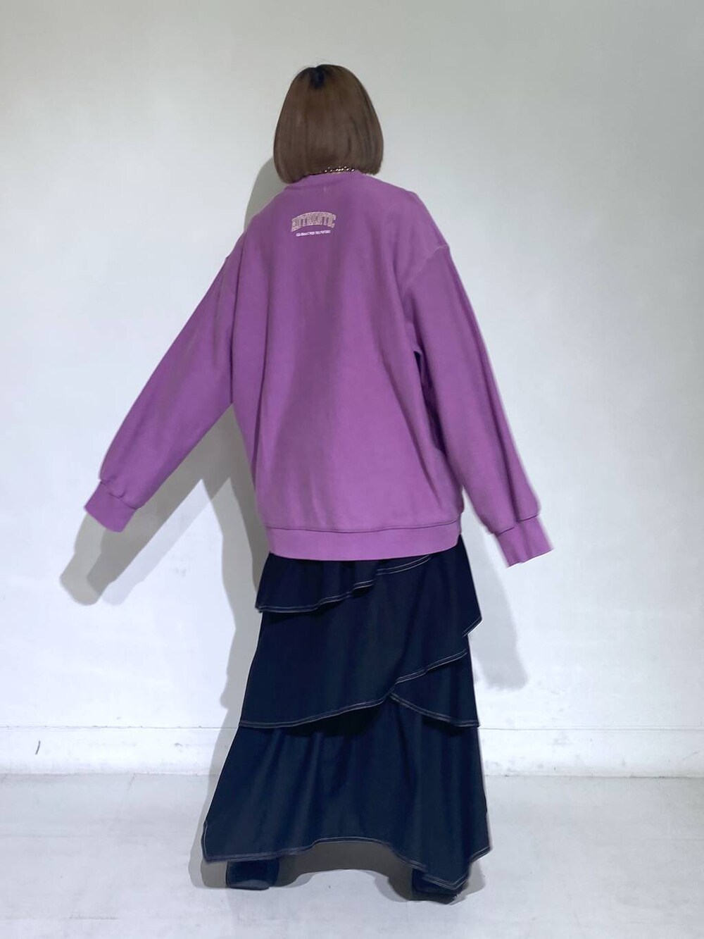 パープル系のスウェット、ホワイト系のブーツ、ブラック系のスカートを着用したレディースの冬コーディネートの3枚目の写真