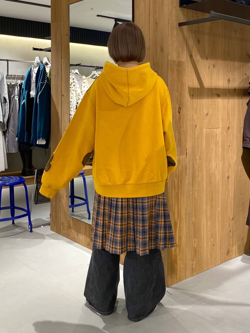 ブラック系のデニムパンツ、イエロー系のパーカー、オレンジ系のスカートを着用したレディースの秋コーディネートの4枚目の写真