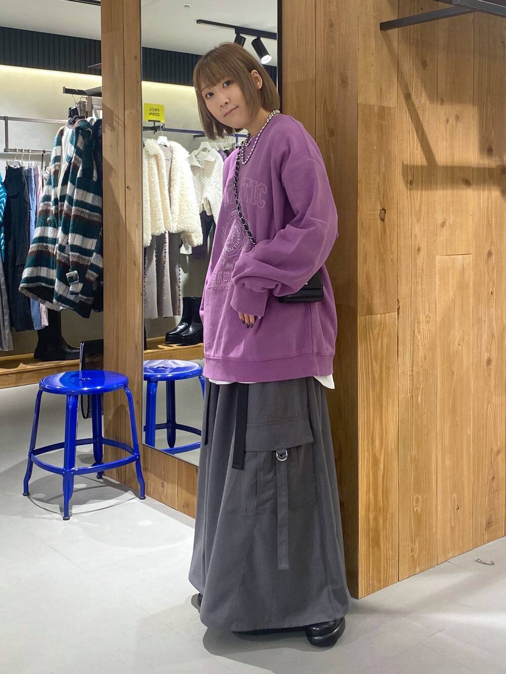 パープル系のスウェット、グレー系のジャンパースカート、ブラック系のブーツを着用したレディースの冬コーディネートの2枚目の写真