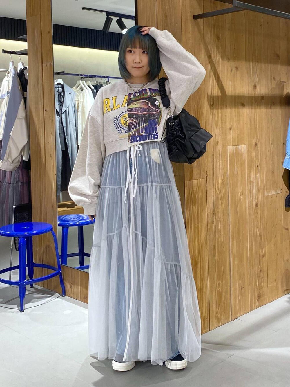 ベージュ系のスウェット、ブルー系のデニムパンツ、ホワイト系のワンピースを着用したレディースの春コーディネートの3枚目の写真