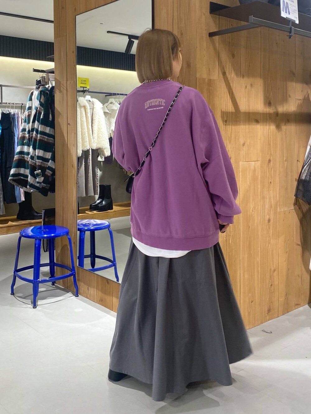 パープル系のスウェット、グレー系のジャンパースカート、ブラック系のブーツを着用したレディースの冬コーディネートの3枚目の写真