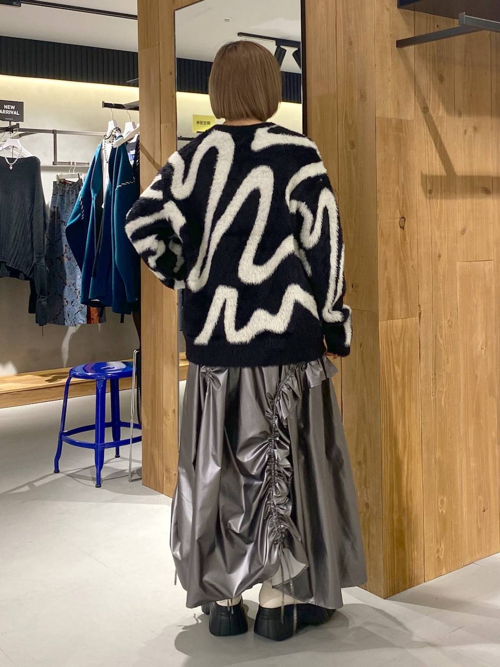 ホワイト系のブーツ、シルバー系のスカート、ブラック系のニット/セーターを着用したレディースの冬コーディネートの2枚目の写真