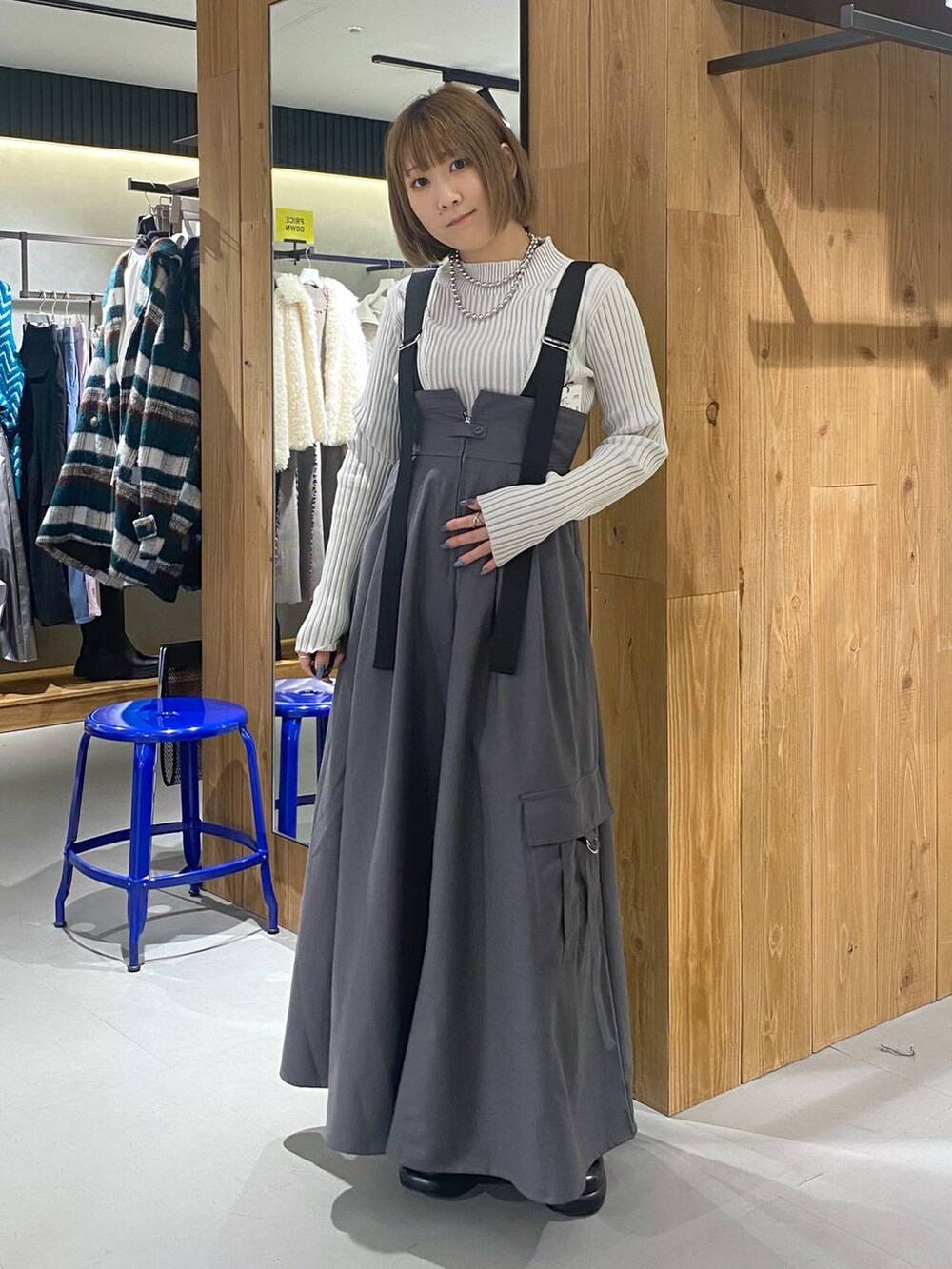 グレー系のジャンパースカート、ブラック系のブーツ、ホワイト系のニット/セーターを着用したレディースの冬コーディネートの3枚目の写真