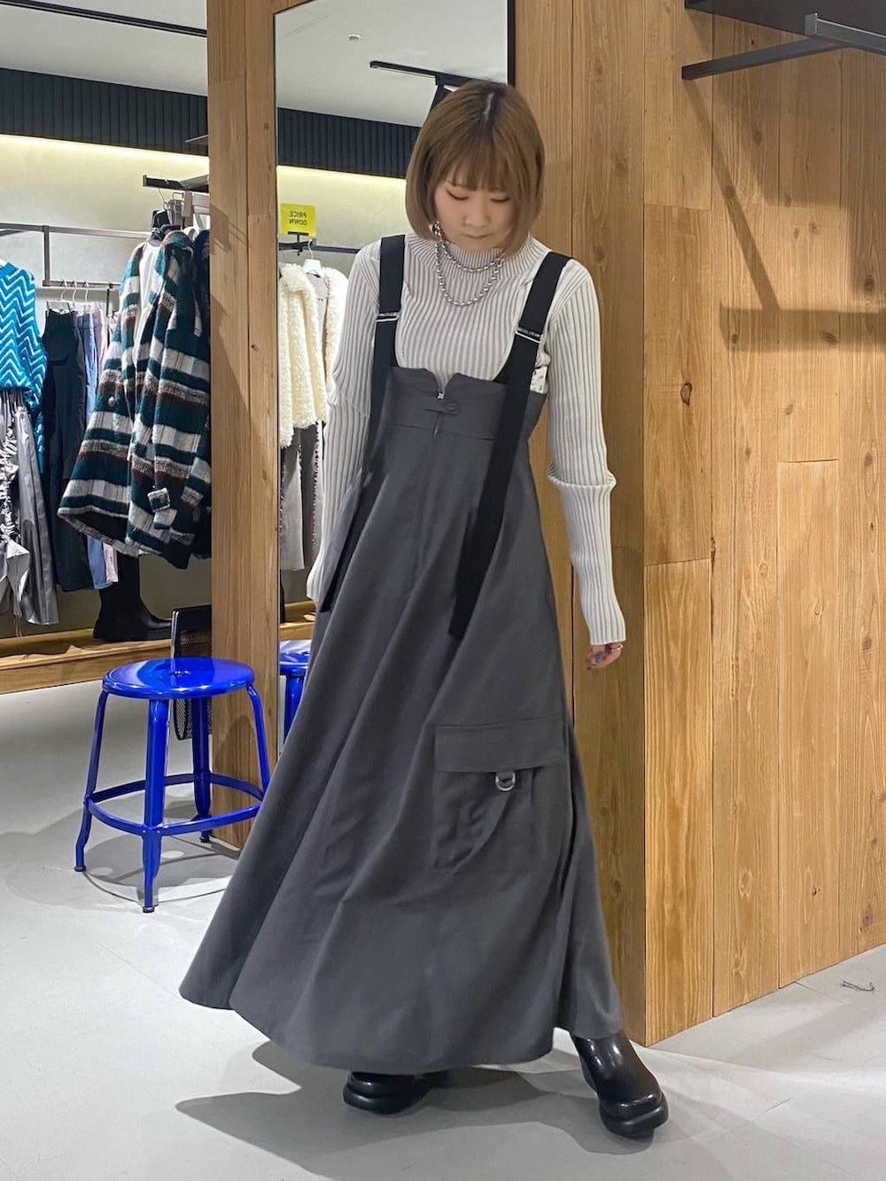 グレー系のジャンパースカート、ブラック系のブーツ、ホワイト系のニット/セーターを着用したレディースの冬コーディネートの4枚目の写真